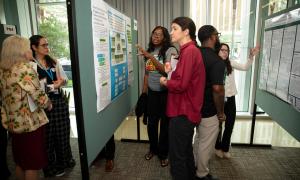 People gathered, discussing academic posters at a conference.