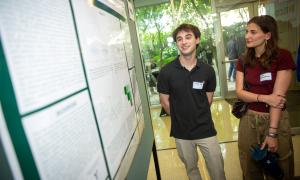 Man and woman standing beside a research poster indoors.