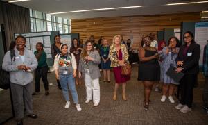 Photograph: Diverse group of smiling people gathered in a conference room with academic posters.