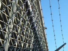 Image of barbed wire, blue sky, prison inference.