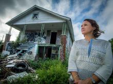 Katherine Theall, Cecile Usdin Professor in Women’s Health, stands next to blighted house. Photo by Paula Burch-Celentano.