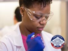 A woman in a lab with the Heed Award logo