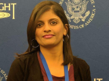 Bhavita Kumari smiling at camera, US government backdrop behind her