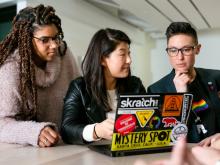 Three diverse women look at a laptop screen covered in decals