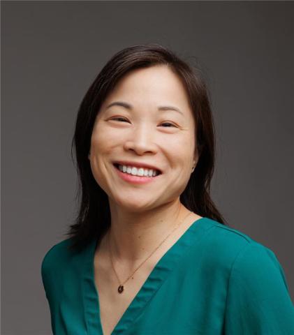 Headshot of Colleen Nguyen, smiling, wearing a green shirt and a gold necklace