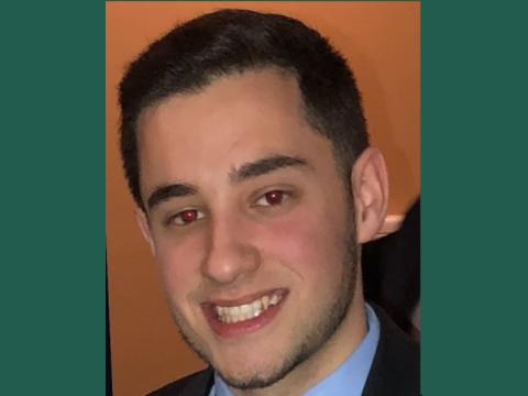 Photograph: Christopher Morelli, smiling, with dark hair, wearing a suit, showing red-eye effect.