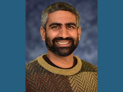 Photo Of Hans DeSale, smiling, wearing gold and brown sweater