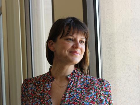 Shay Slifko, PhD student, smiling, standing near a window