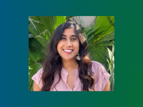 Tejal Patel outside in sunshine with palm trees in background, wearing a pink shirt